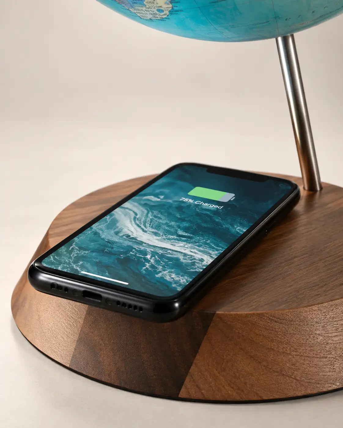 Zoffoli Bridge: detail of a smartphone showing a charging symbol on the Aquamarine globe's wooden base.