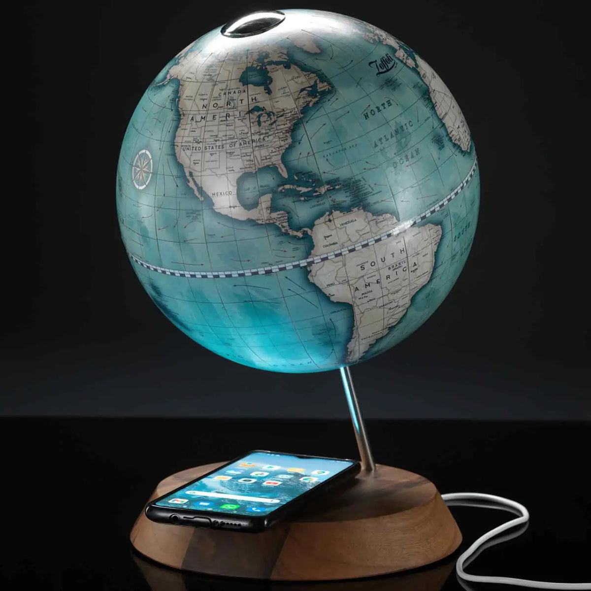 Zoffoli Bridge: Indigo globe with a smartphone resting on the wooden wireless charging base.