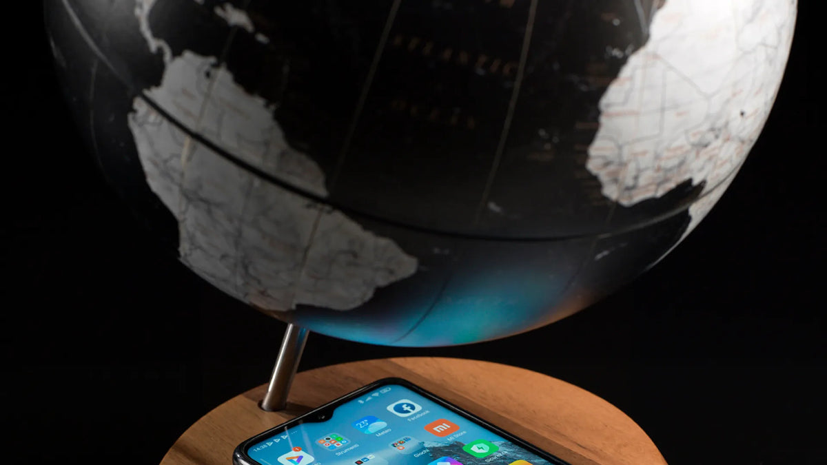 Zoffoli Bridge: Black globe above a smartphone on its wooden charging base against a dark background.
