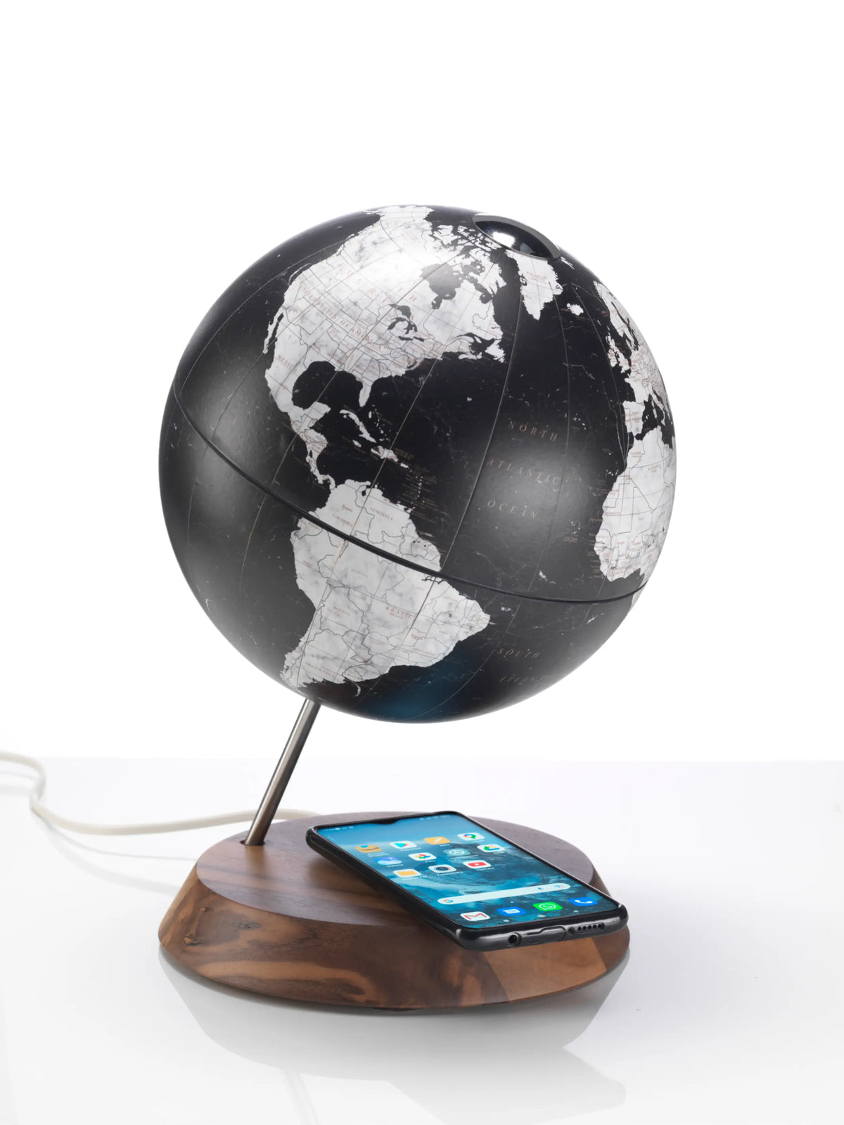 Zoffoli Bridge: Black desk globe with a monochrome map and smartphone on its wireless charging base.
