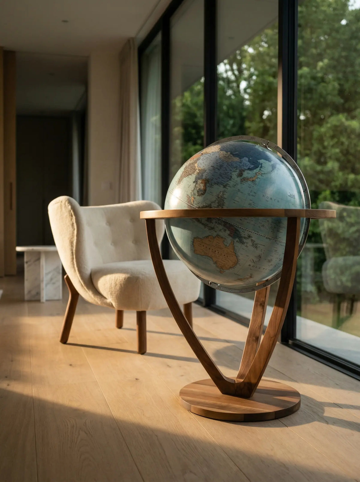 Zoffoli Trilogy: Aquamarine decorative globe beside an armchair and large window.