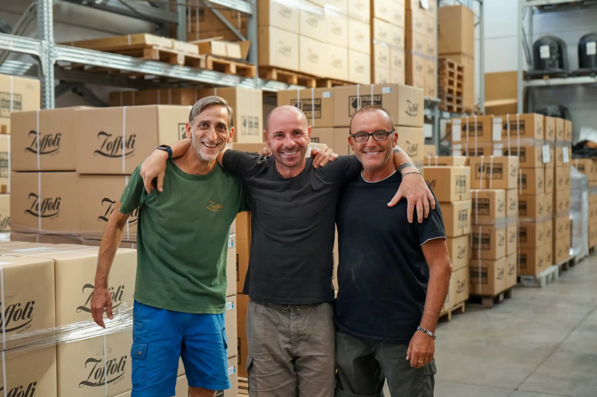 Tre persone nel reparto di produzione Zoffoli tra sfere e casse per mappamondi.