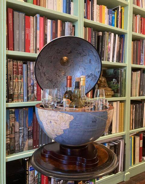 Mappamondo bar Zoffoli con sfera azzurra aperto davanti a una libreria.