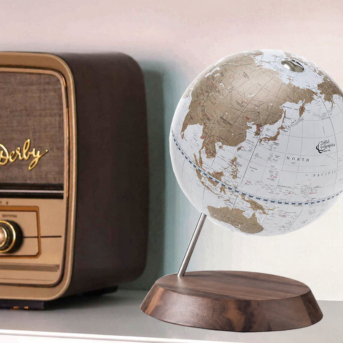 Zoffoli Desk: Gold decorative desk globe beside a vintage radio on a wooden table.